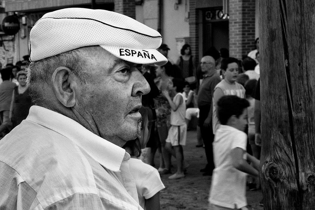 A man wearing a cap bearing the word España among a crowd.